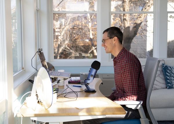 Joshua smiling at his microphone during the virtual launch of Dare to Be Naive